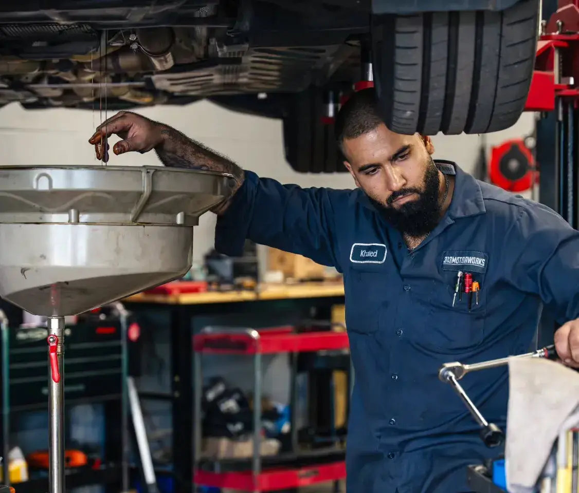 Khaled fixing a car with oil on his hand